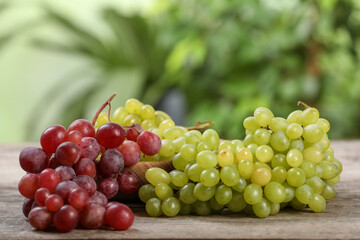 Different fresh ripe grapes on wooden table against blurred background, space for text