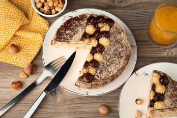 Delicious Kyiv Cake decorated with cream and hazelnuts served on wooden table, above view