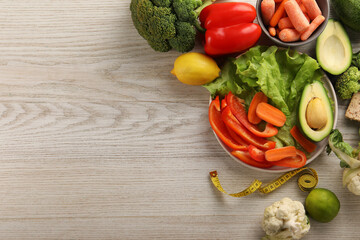 Healthy diet. Fresh vegetables and measuring tape on light wooden table, flat lay. Space for text