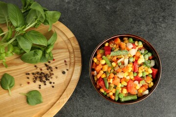 Different frozen vegetables, spices and fresh basil on grey table, flat lay