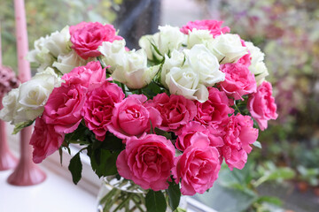 Vase with beautiful bouquet of roses and candles on windowsill indoors, closeup