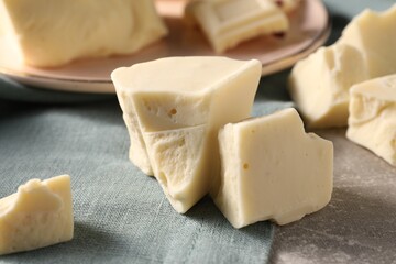 Pieces of tasty white chocolate on grey table, closeup