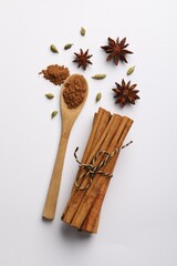 Cinnamon sticks, star anise and cardamom pods on white background, flat lay