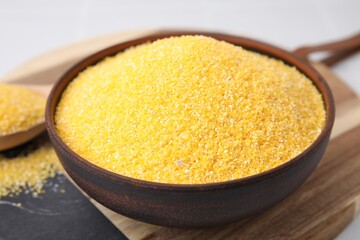 Raw cornmeal in bowl on table, closeup