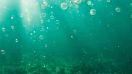Underwater view of water surface and floor with bubbles. Green ocean background.