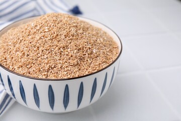 Dry wheat groats in bowl on white table, closeup. Space for text