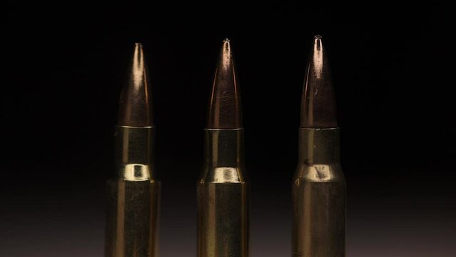 3 bullets on a row - macro shot - with swaying flames in the background - shot in slow motion