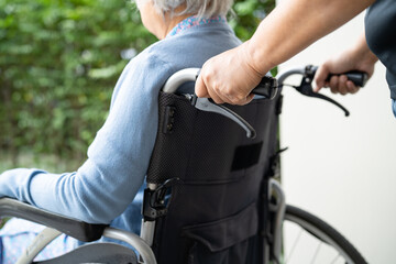 Obraz premium Caregiver help and care Asian senior woman patient sitting on wheelchair to ramp in nursing hospital, healthy strong medical concept.