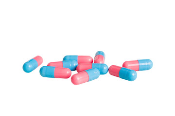 Heap of pink and blue pills on colored background. Tablets scattered on a table. Pile of red soft...
