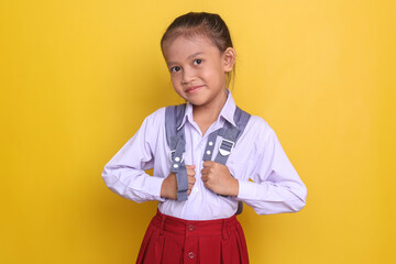Portrait of confident little asian girl in school uniform carrying backpack and looking at camera smiling
