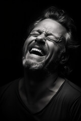 Expressive monochrome: A close-up portrait of a laughing mature European with his head thrown back Against a Black Background, capturing strong emotions in black and white