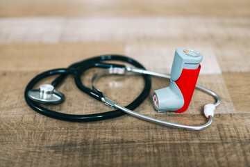 Asthma inhaler and stethoscope on wooden table 