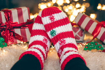 Feet in wool socks near fireplace in winter time, resting at home, close up.