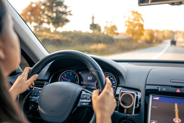 Woman driver hands on steering wheel inside car.