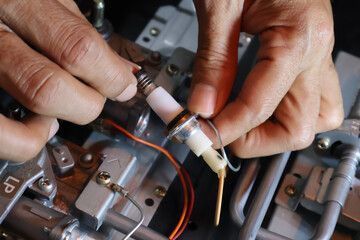 Close up of a technician's hand repairing a broken cooktop or stovetop