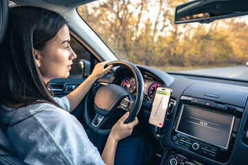 Woman using navigation app on smartphone while driving a car.