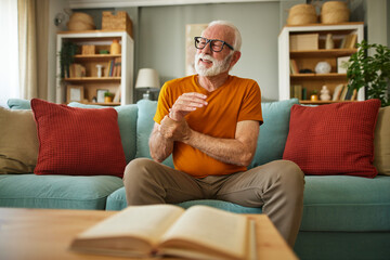 Obraz premium Elderly man suffering from his wrist joint pain at home