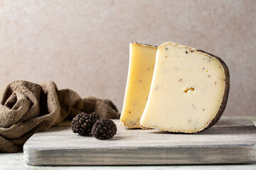 Wooden board with aged sheep's milk pecorino cheese with black truffles flakes. Fresh whole...