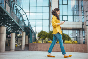 Shot of a beautiful mature businesswoman texting. Mature businesswoman walking outdoors and using cellphone. Female business professional walking outside and texting from her mobile phone.