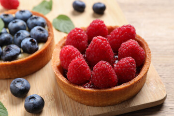 Tartlet with fresh raspberries on wooden board, closeup. Delicious dessert