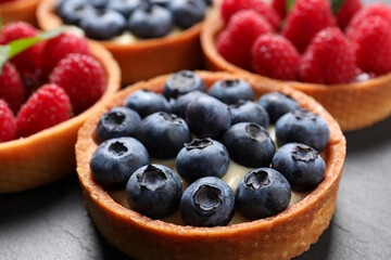 Tartlet with fresh blueberries on black table, closeup. Delicious dessert