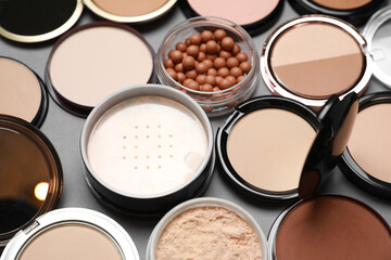 Different face powders on grey background, closeup