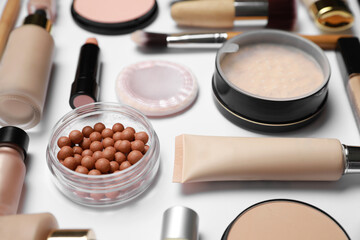 Face powders and other makeup products on white background, closeup
