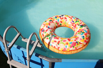 Inflatable ring floating on water in above ground swimming pool outdoors
