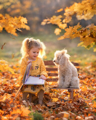 Little girl child and dog in autumn forest. Female kid and pet portrait at nature with yellow...