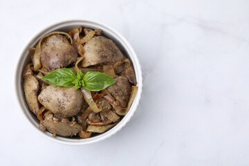 Delicious fried chicken liver with onion and basil in bowl on white marble table, top view. Space for text