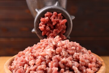 Manual meat grinder with beef mince against blurred background, closeup