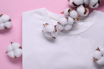 Cotton branch with fluffy flowers and white t-shirt on pink background, flat lay