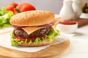 Tasty hamburger with patty, cheese and vegetables served on table, closeup