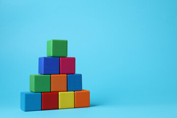 Pyramid of blank colorful cubes on light blue background. Space for text