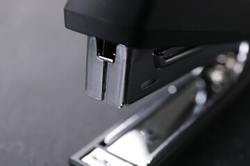 Fototapeta na wymiar One black stapler on gray background, closeup