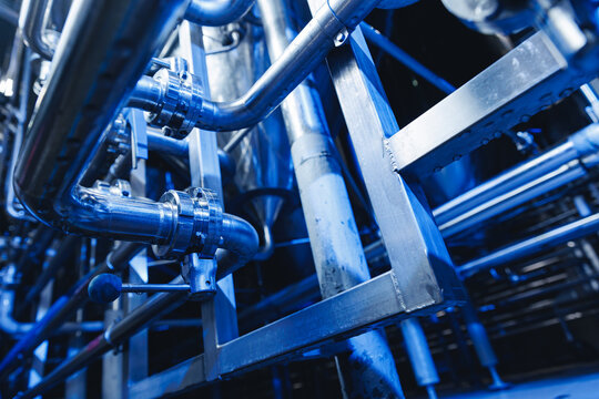Pipes stainless steel brewing equipment, large reservoirs or tanks in modern beer factory. Brewery production concept, industrial blue background