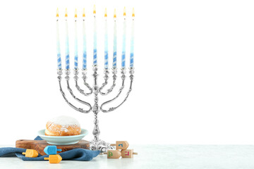 Hanukkah celebration. Menorah with colorful candles, dreidels and donuts on white background