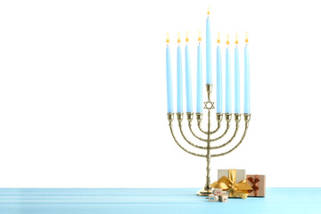Hanukkah celebration. Menorah, dreidels and gift boxes on light blue wooden table against white background
