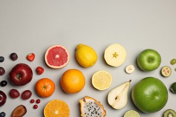 Different ripe fruits and berries on light gray background, flat lay. Space for text - obrazy, fototapety, plakaty