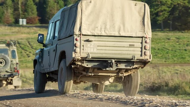 a convoy of British army Wolf utility vehicles, a MAN SV4x4 truck and a Supacat Coyote moving down a dirt road