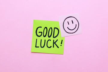 Sticky note with Good Luck handwriting on pink background.