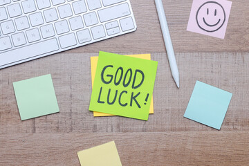 Sticky note with Good Luck handwriting on office work desk.