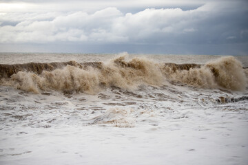 Large waves hit the shore. Storm at sea, storm warning on the coast. Thunderclouds and large sea waves during a storm.
