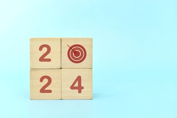 Year 2024 business target concept. Human hand stacking wooden blocks with 2024 target icon.	
