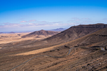 View of a road that runs through several mountains through the desert. Photography taken in Fuerteventura, Canary Islands, Spain.