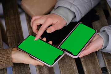 Top view close-up of smartphones held by female hands. Two girls in sportswear in outerwear at a...