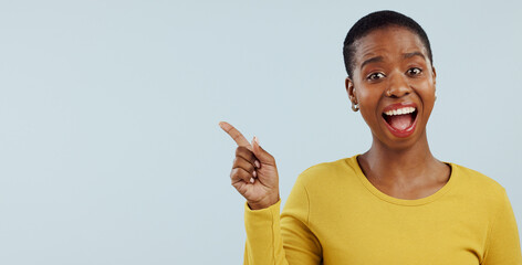 Happy black woman, portrait and pointing in surprise for advertising or marketing against a gray...