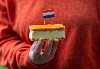 Orange Tompouce in hand, selective focus. A popular pastry eaten in The Netherlands during King's Day celebrations