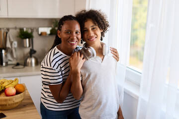Portrait of embraced teenage boy and his mother at home
