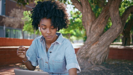 Teenager headphones turning music at smartphone sitting park with laptop closeup